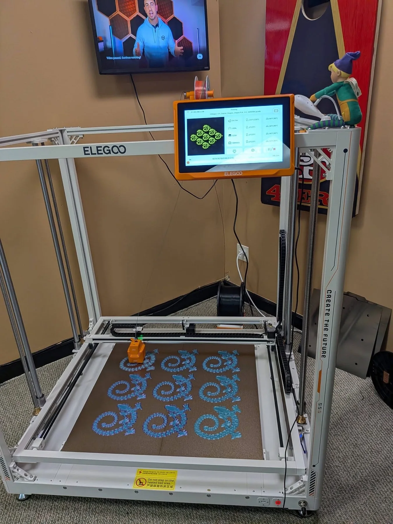 3D printer producing a tray of small character-shaped prints.