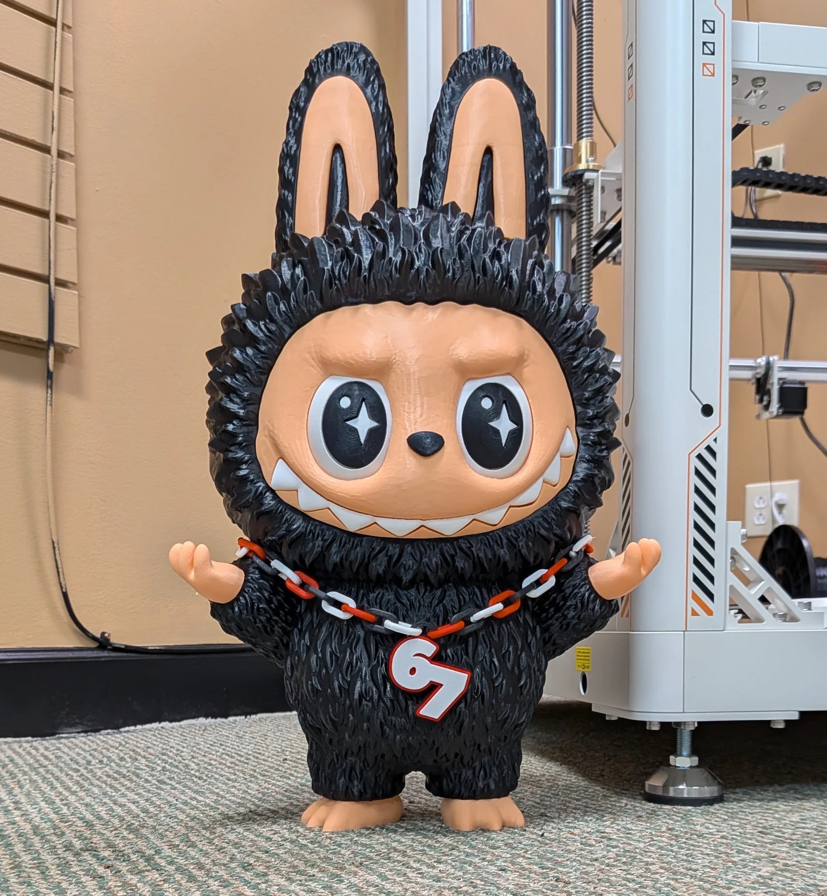 Collectible 3D-printed character figure displayed next to a printer in the shop.