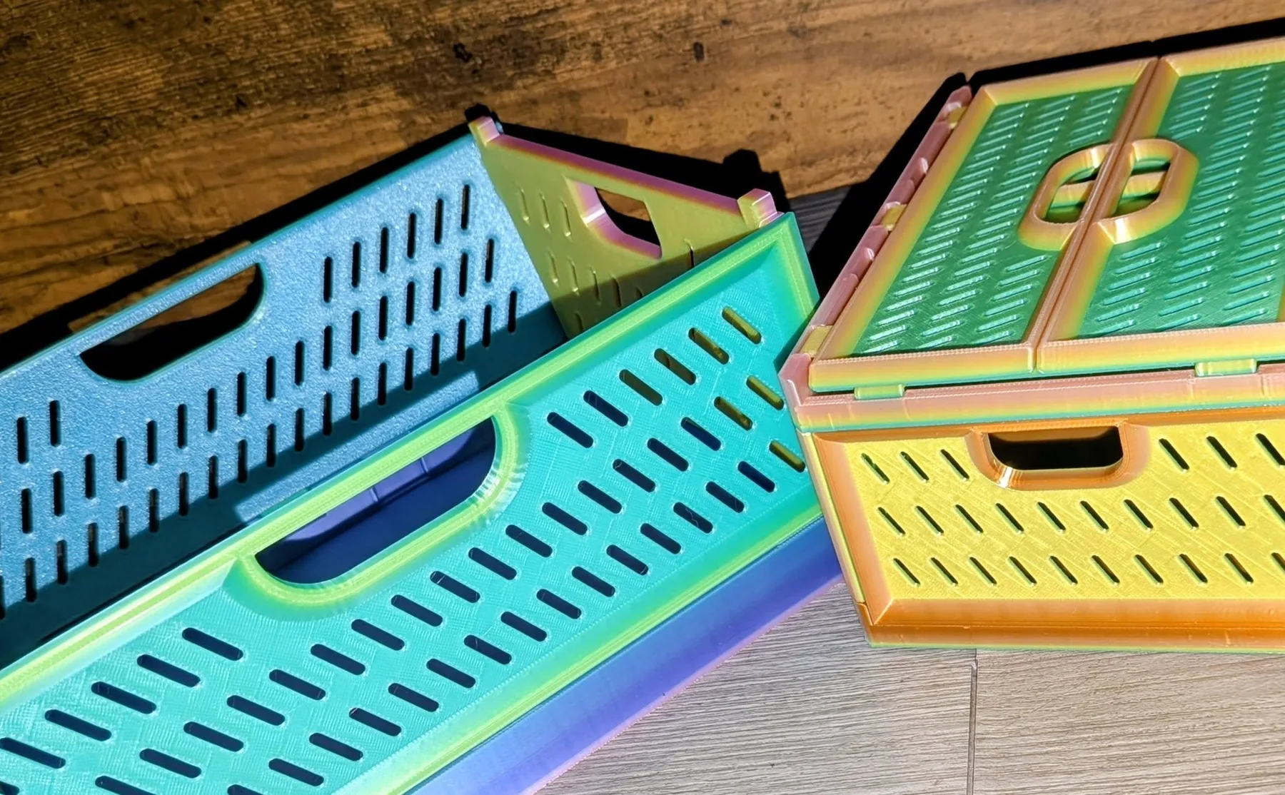 Stack of colorful iridescent 3D-printed storage boxes with slotted vents and cutout handles.