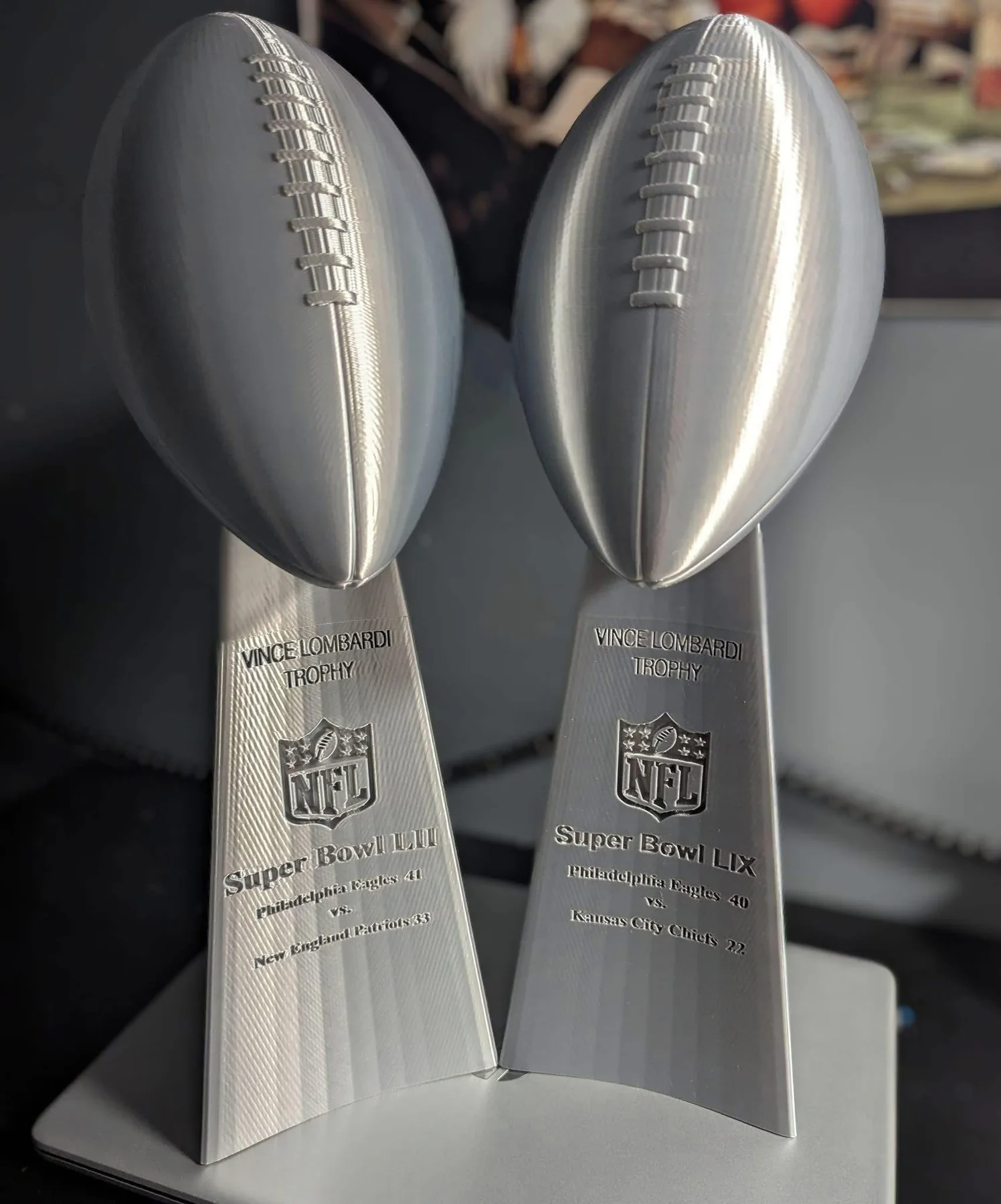 Silver football-shaped custom trophies on display.