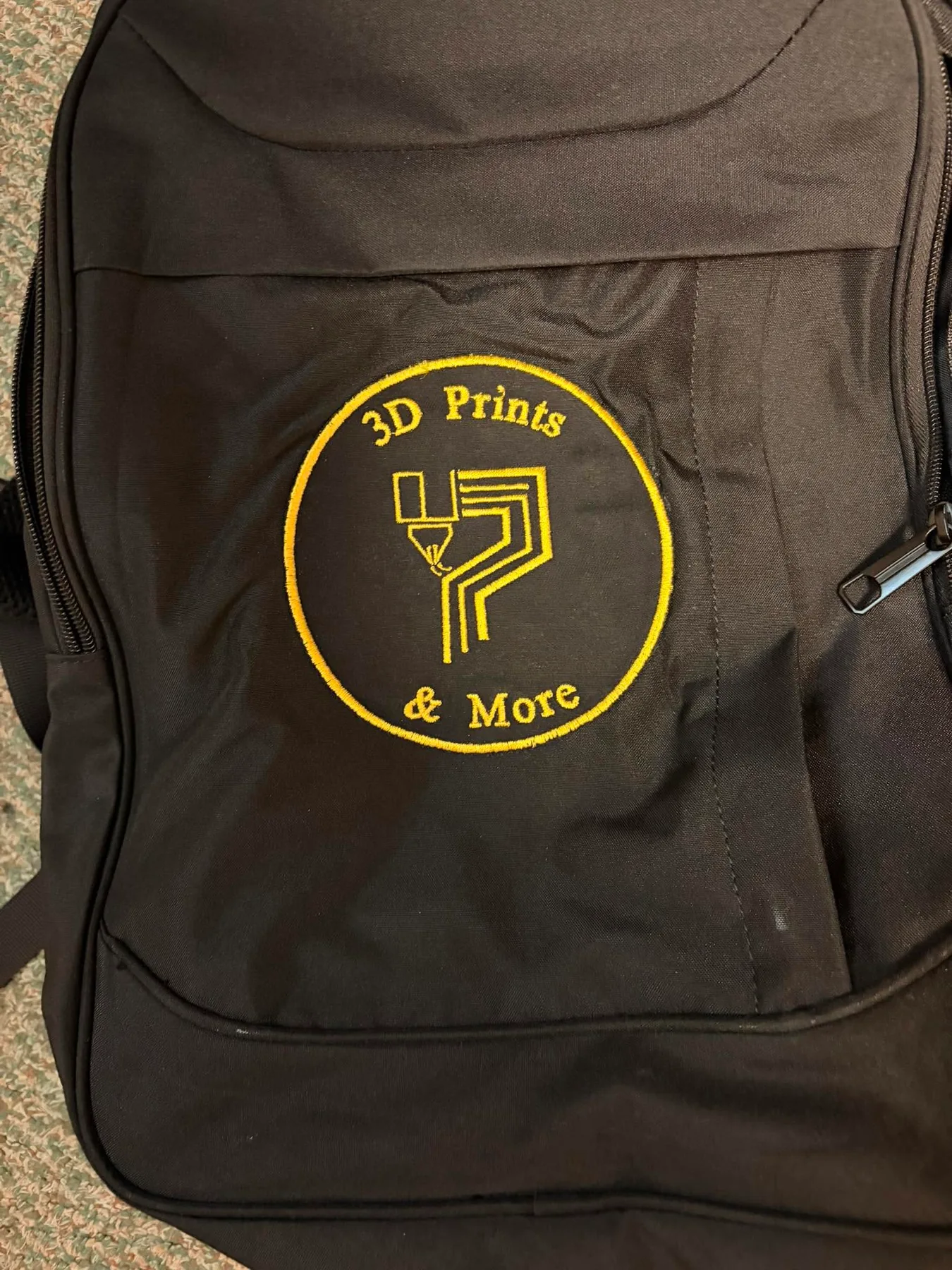 Backpack displaying the merchant's own 3D Prints and More logo in gold thread.