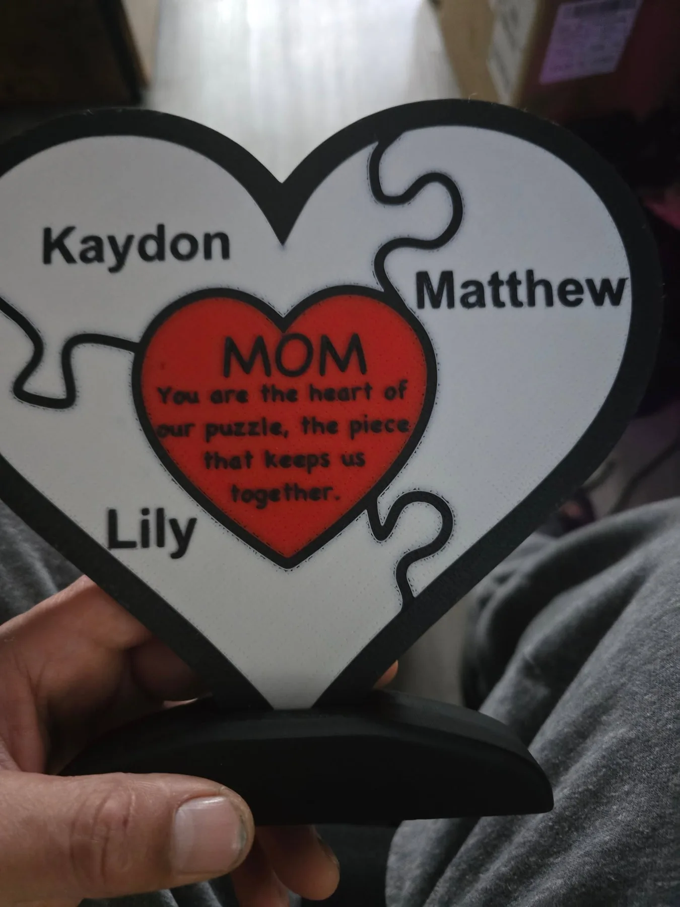 Heart-shaped puzzle-piece sign personalized with family members' names and a message for Mom.