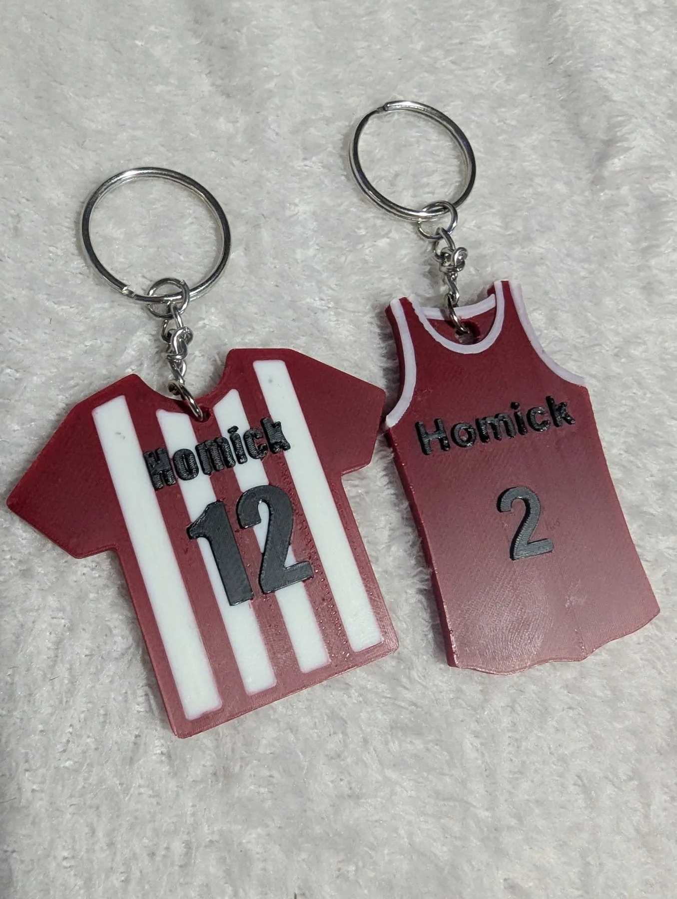 Two jersey-shaped keychains printed with a family name and numbers.