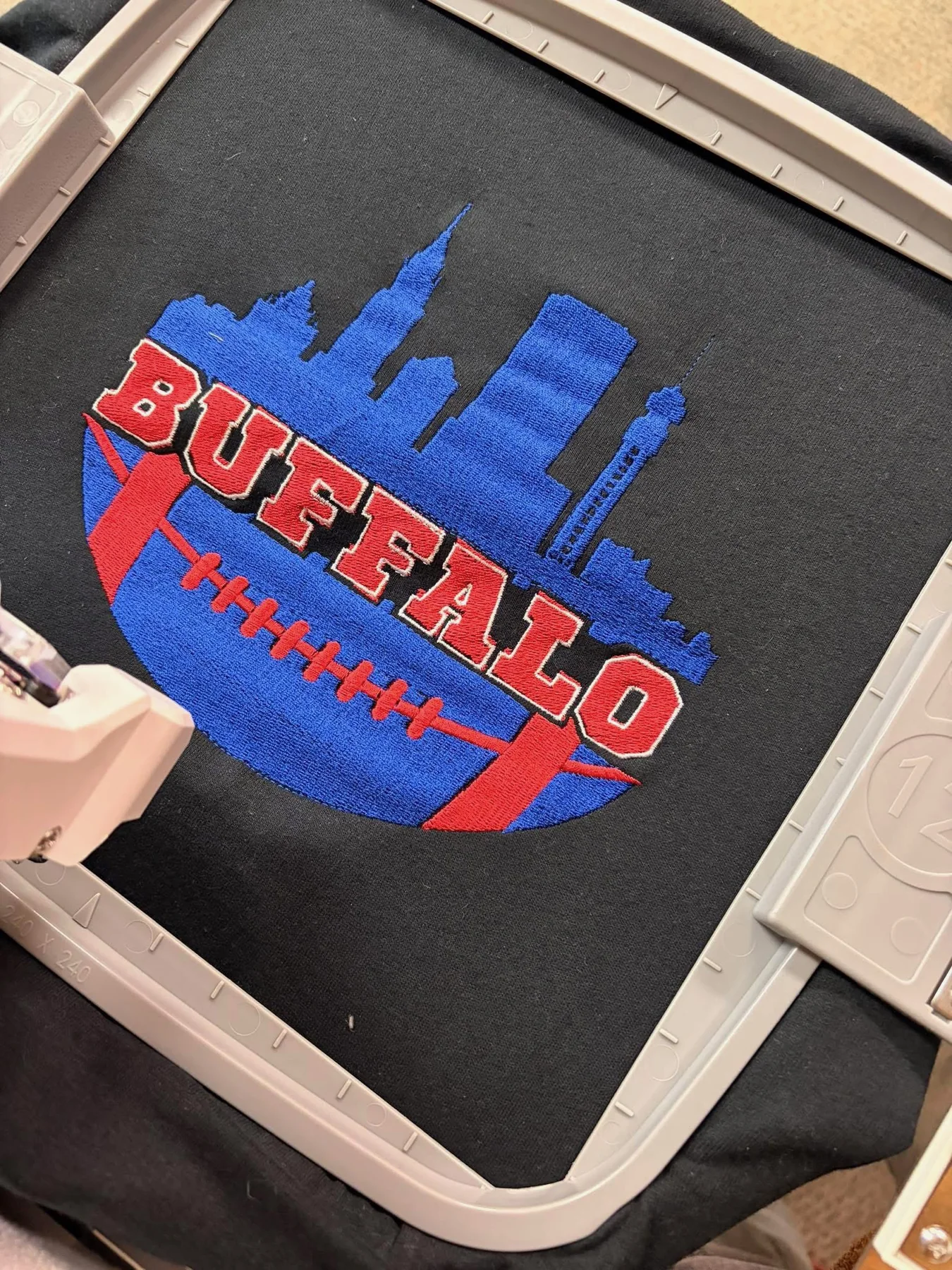 Custom sports-themed embroidered design being stitched on a black shirt.